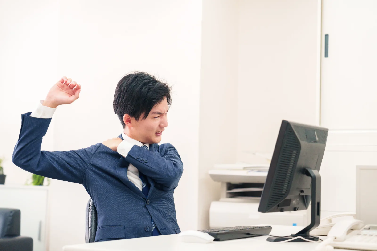 オフィスで肩こりに悩む男性ビジネスマン